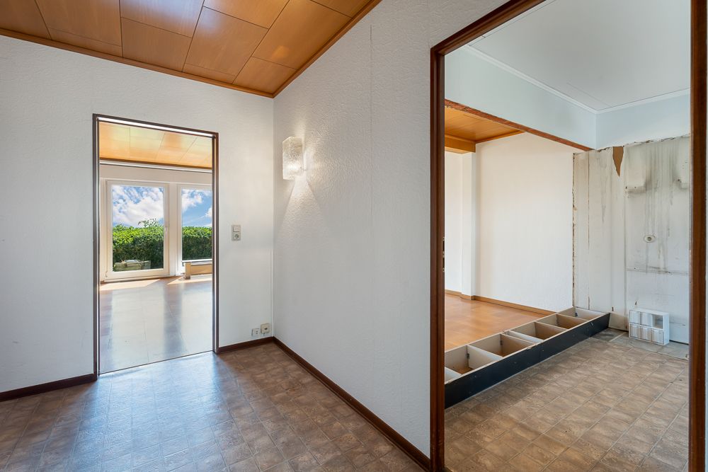 Blick in drei helle Zimmer mit großen Fenstern, Parkett- und Fliesenboden, Holzdecke und Wandlampe.