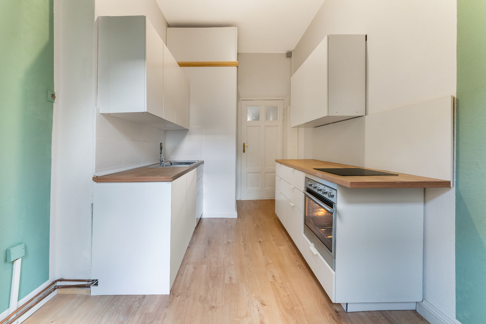 Moderne Einbauküche mit weißen Schränken, Holzarbeitsplatten und Elektroherd.