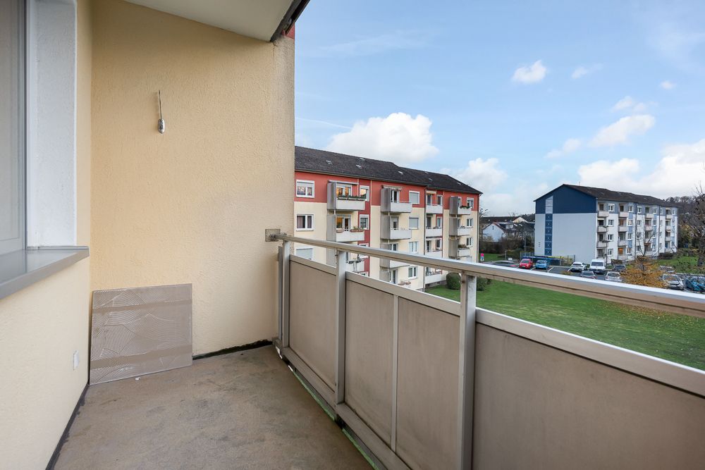 Balkon mit Blick auf Wohngebäude und Rasenfläche.