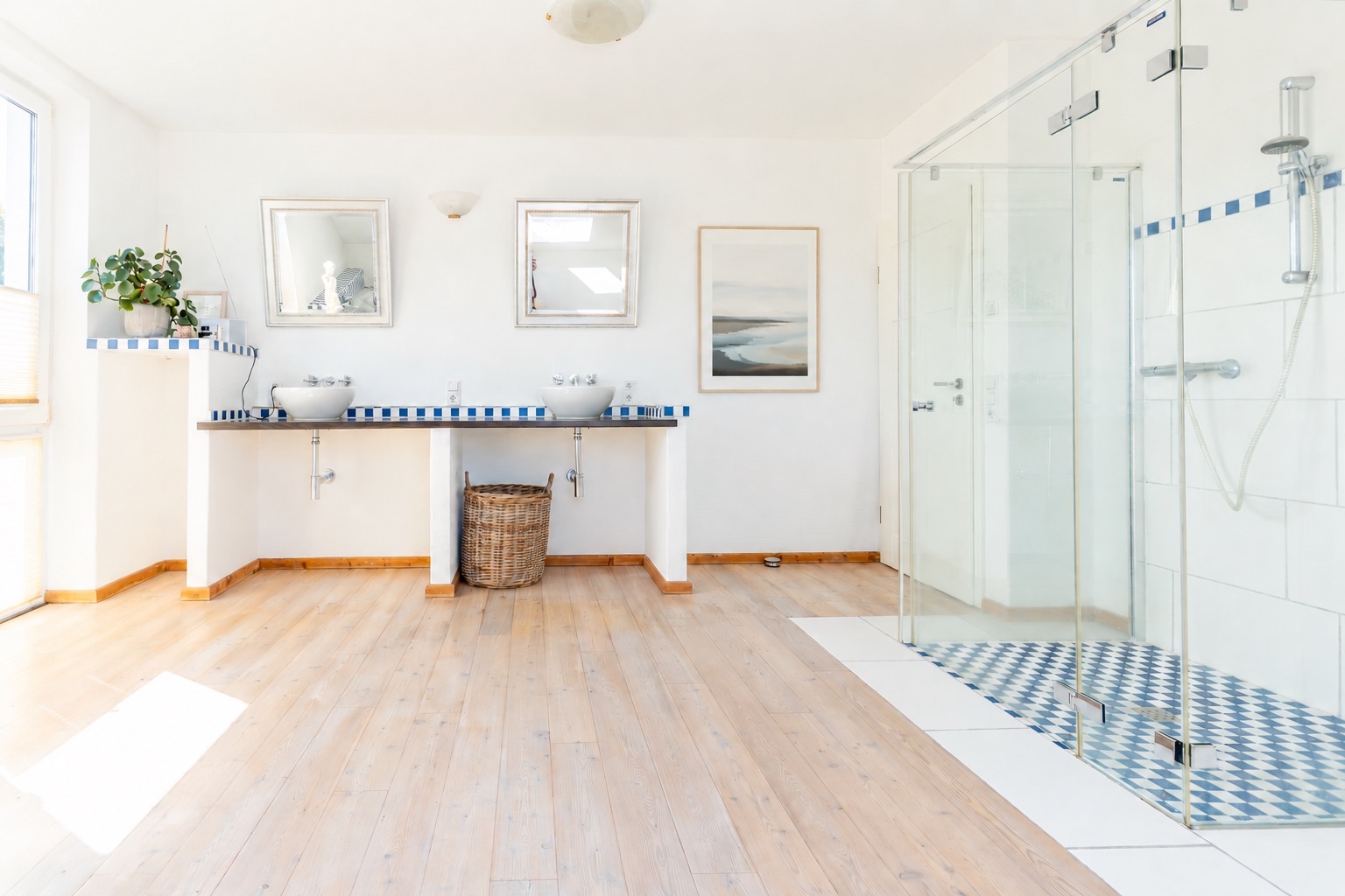 Helles Badezimmer mit zwei Waschbecken, Glasdusche, Spiegeln und Holzboden.