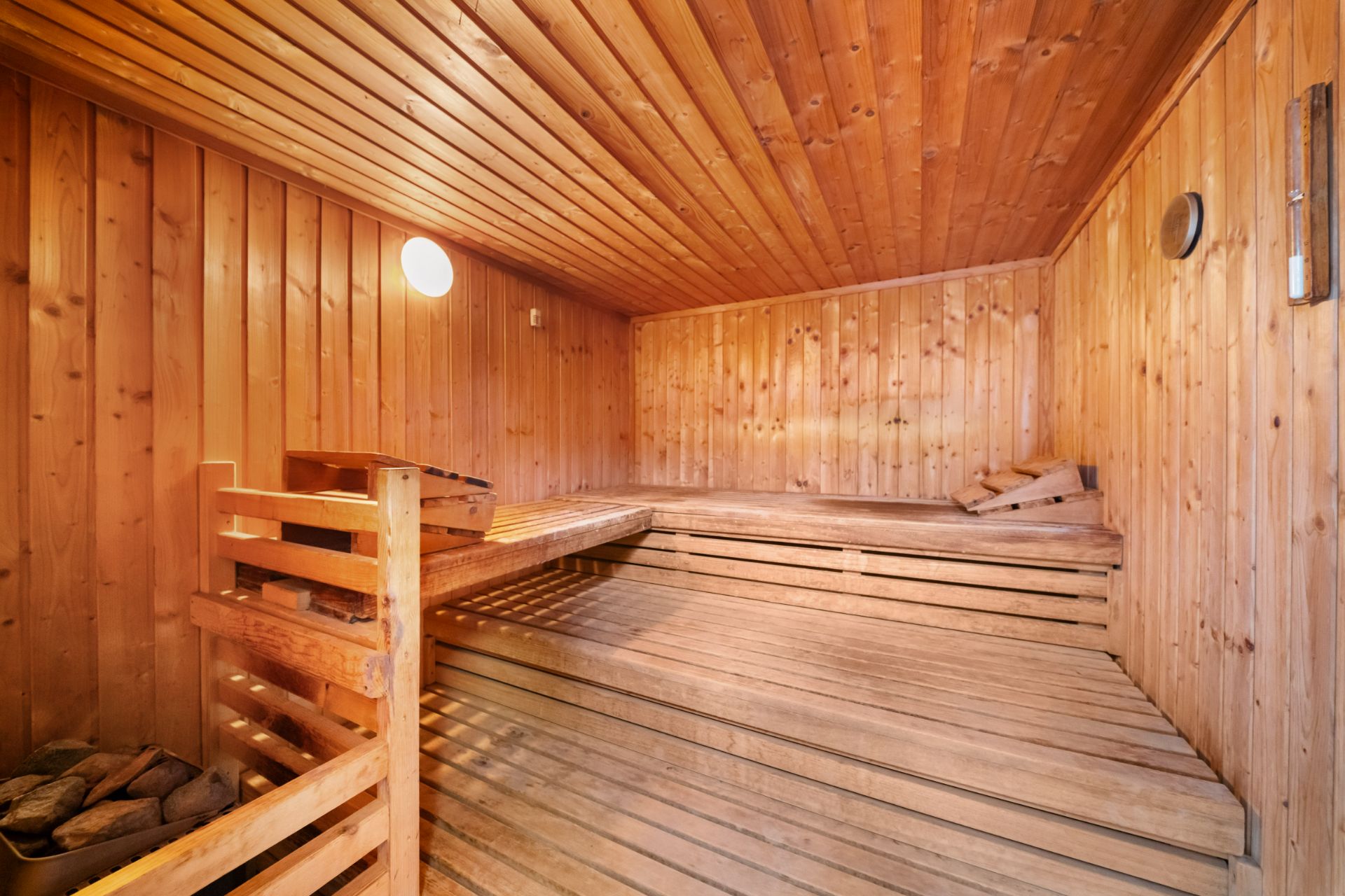 Holzsauna mit Sitzbänken und warmem Licht in einem Wohnhaus.