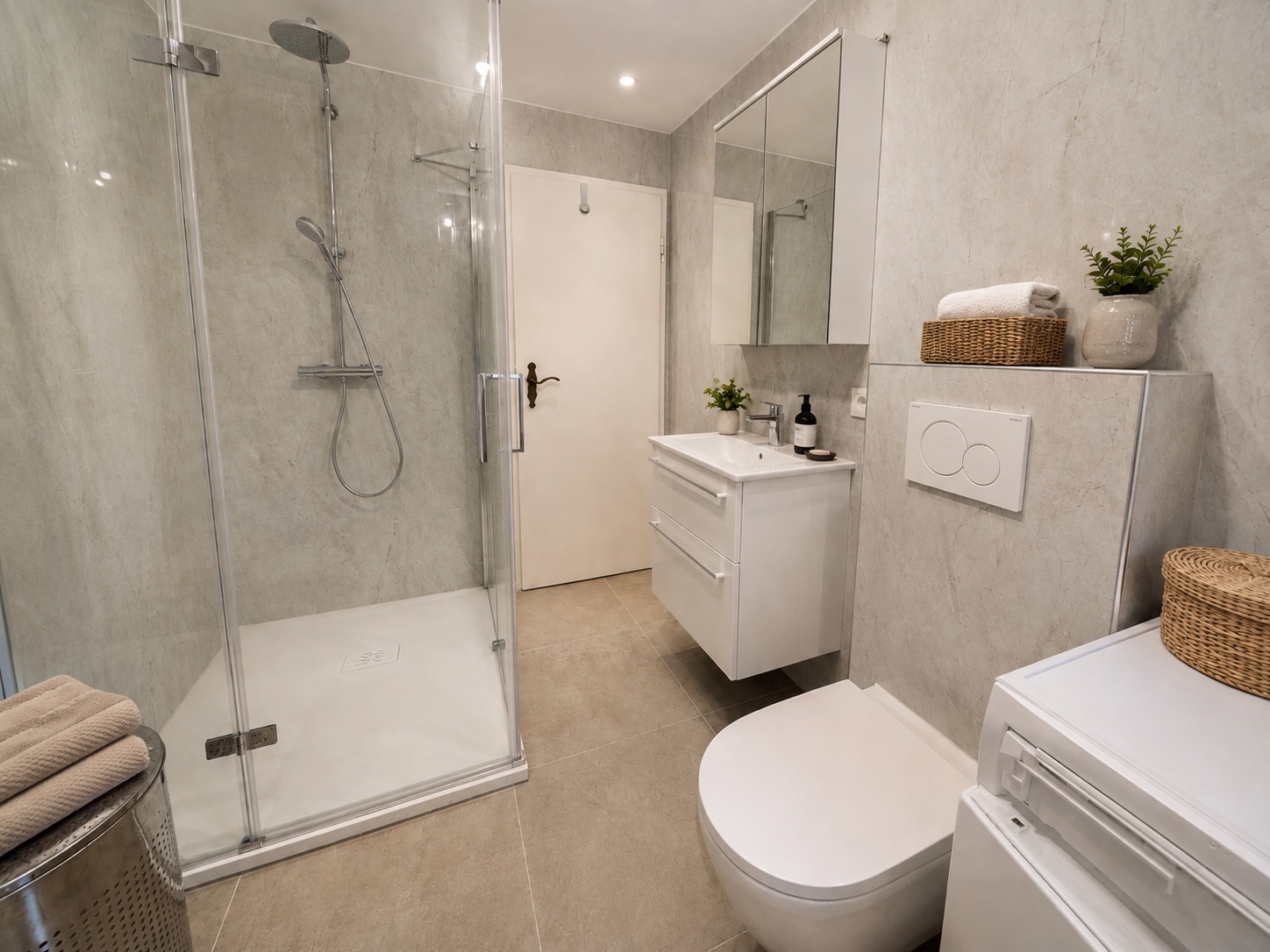 Modernes Badezimmer mit Dusche, Waschbecken, Spiegel, WC und Waschmaschine.