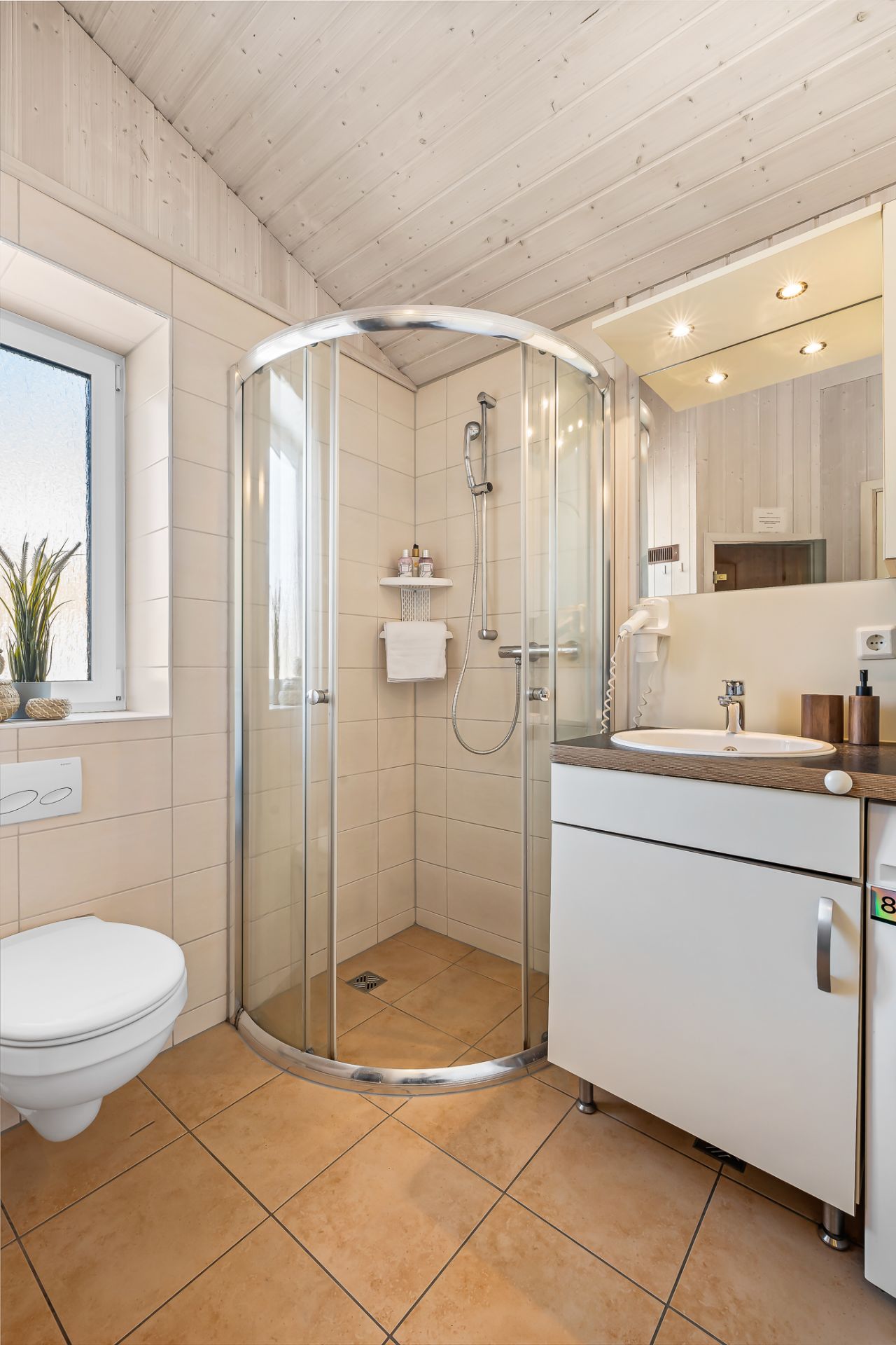 Modernes Badezimmer mit runder Duschkabine, Waschbecken, Spiegel und Toilette.