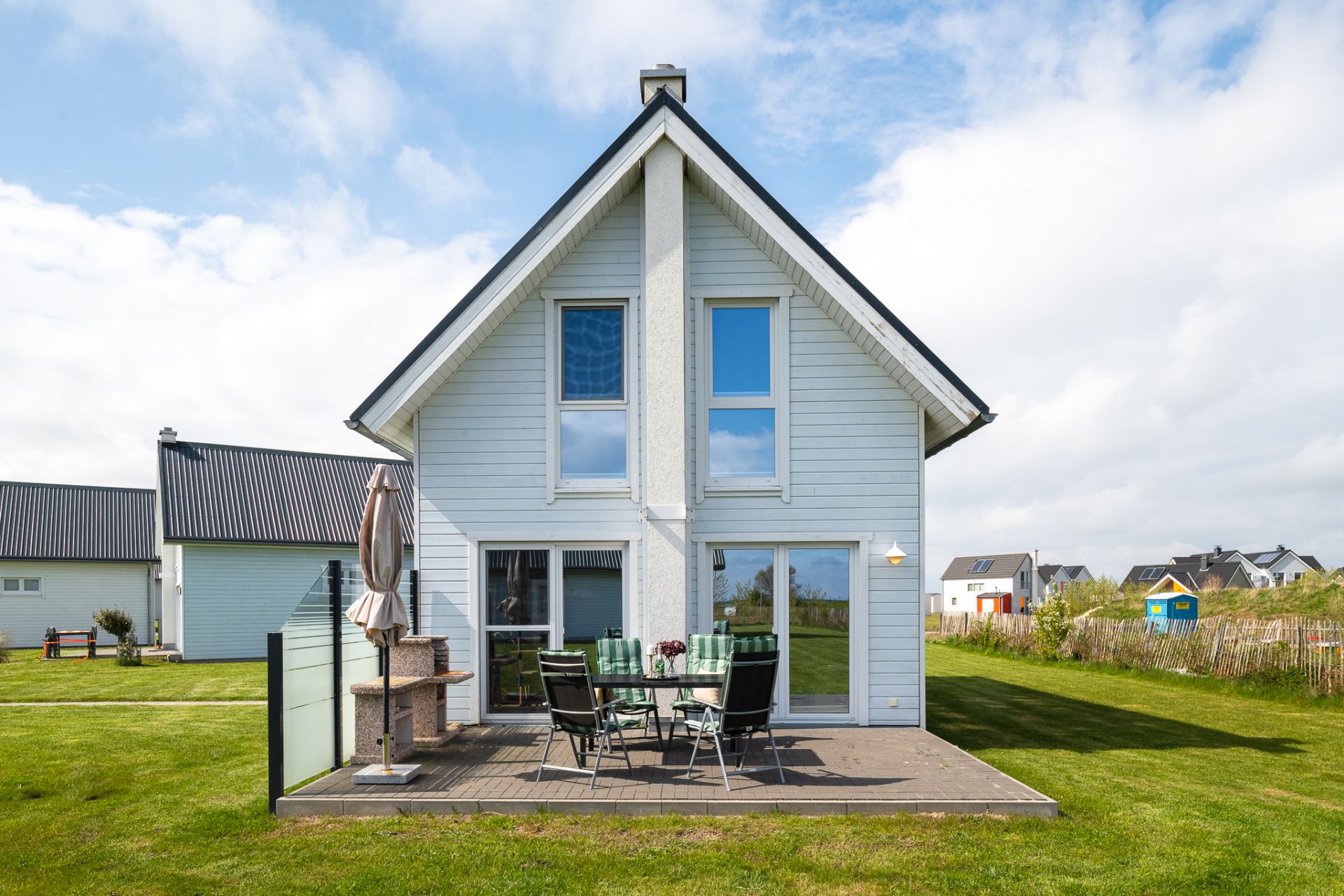 Modernes Einfamilienhaus mit Terrasse, Gartenmöbeln und Grill im gepflegten Garten.