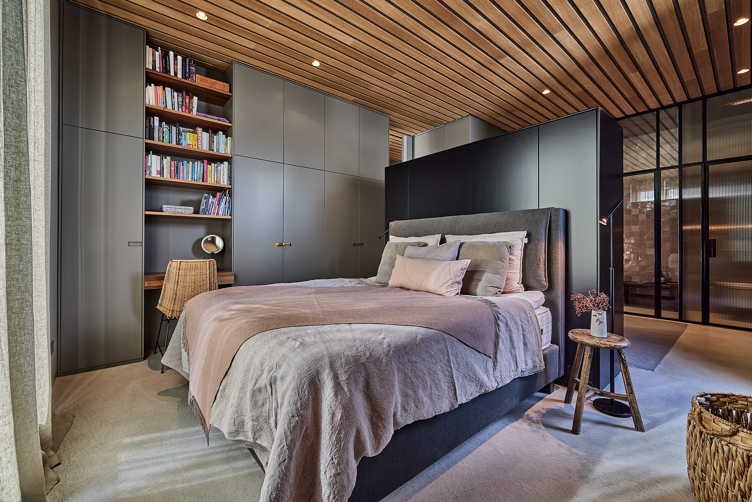 Modernes Schlafzimmer mit Doppelbett, Bücherregal, Schreibtisch und großen Einbauschränken.