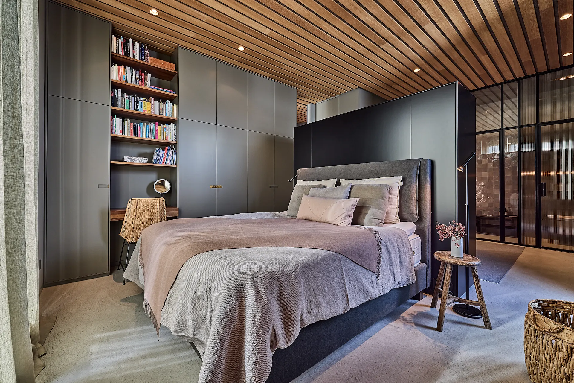 Modernes Schlafzimmer mit Doppelbett, Bücherregal, Schreibtisch und großen Einbauschränken.