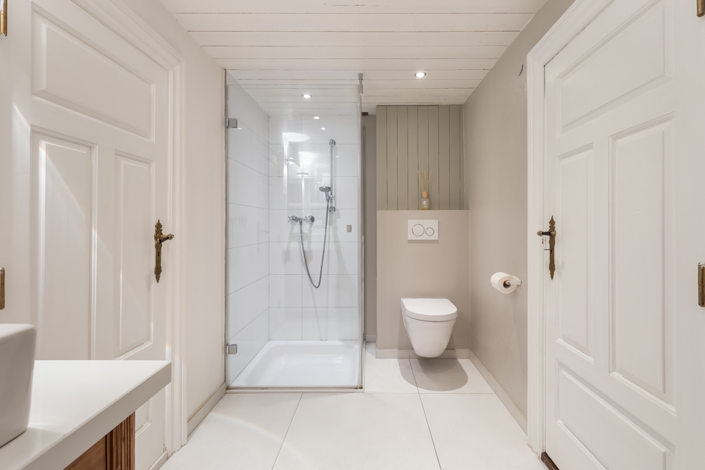 Modernes Badezimmer mit Dusche, Wand-WC und weißen Türen.