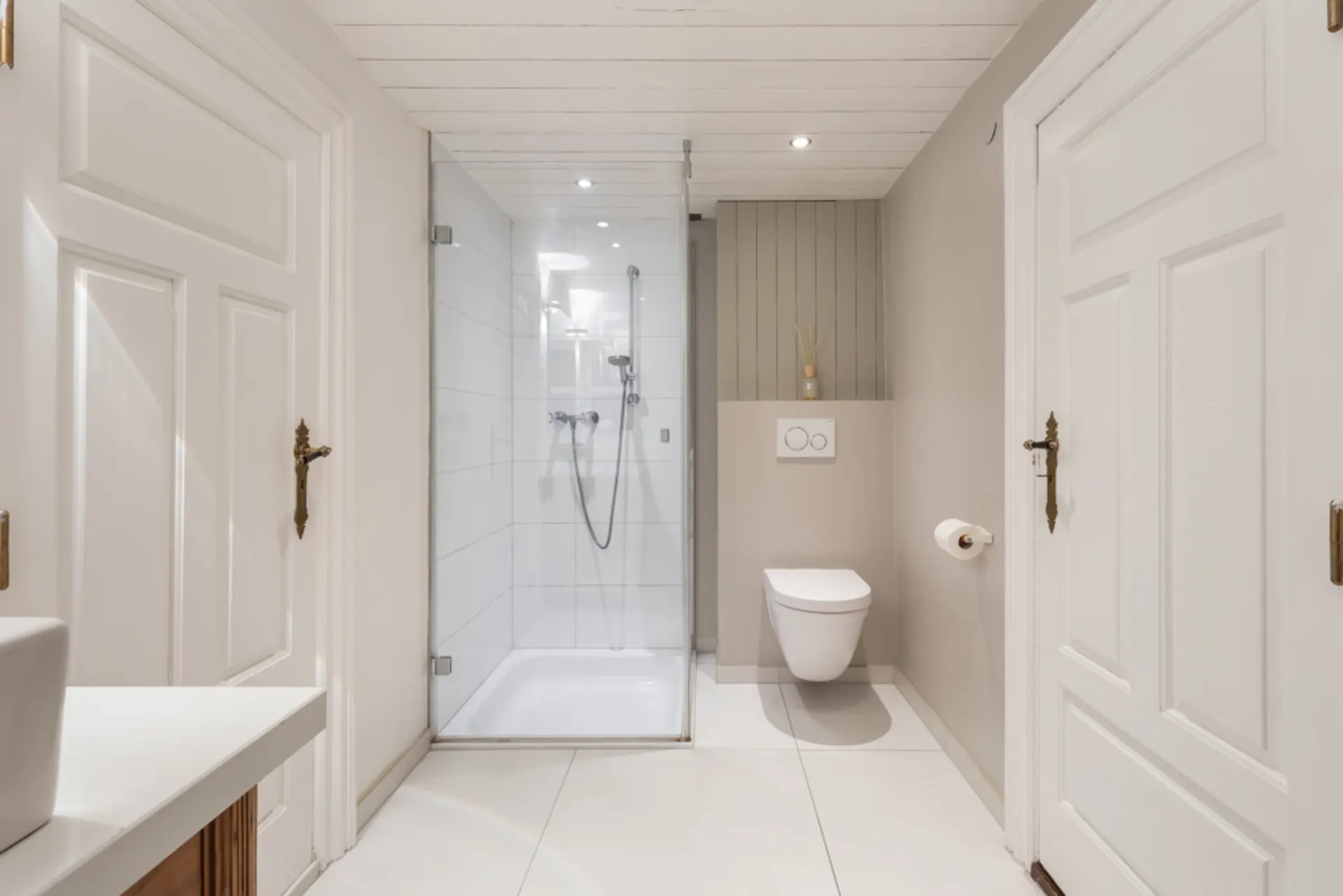 Modernes Badezimmer mit Dusche, Wand-WC und weißen Türen.