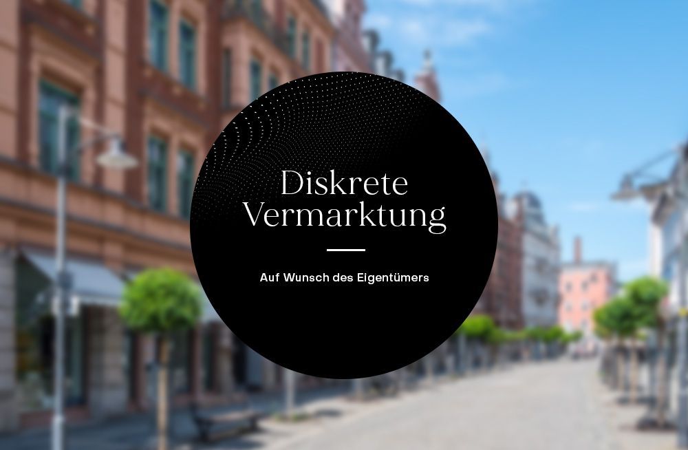 Unscharfe Straße mit Häusern und Bäumen, zentraler schwarzer Kreis mit Text zur diskreten Vermarktung.