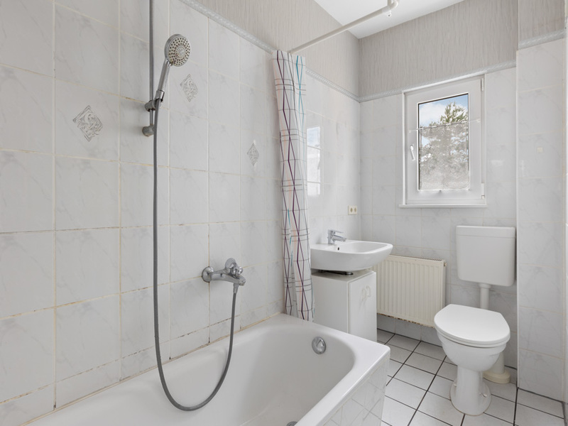 Helles Badezimmer mit Badewanne, Dusche, Waschbecken, Toilette und Fenster.