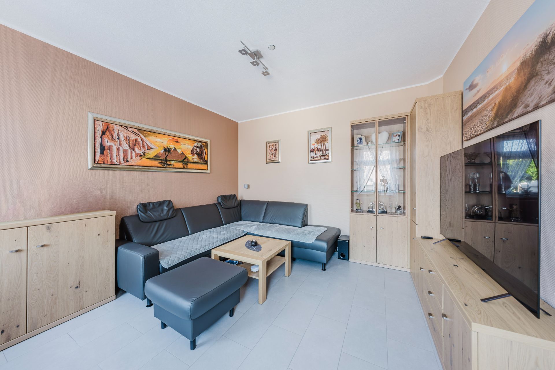 Modernes Wohnzimmer mit Ecksofa, Couchtisch, Fernseher und Holzschränken.