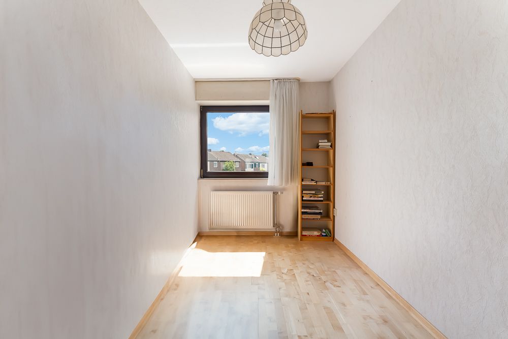 Schmaler Raum mit Holzregal, Fenster, Vorhang und Licht an der Decke.