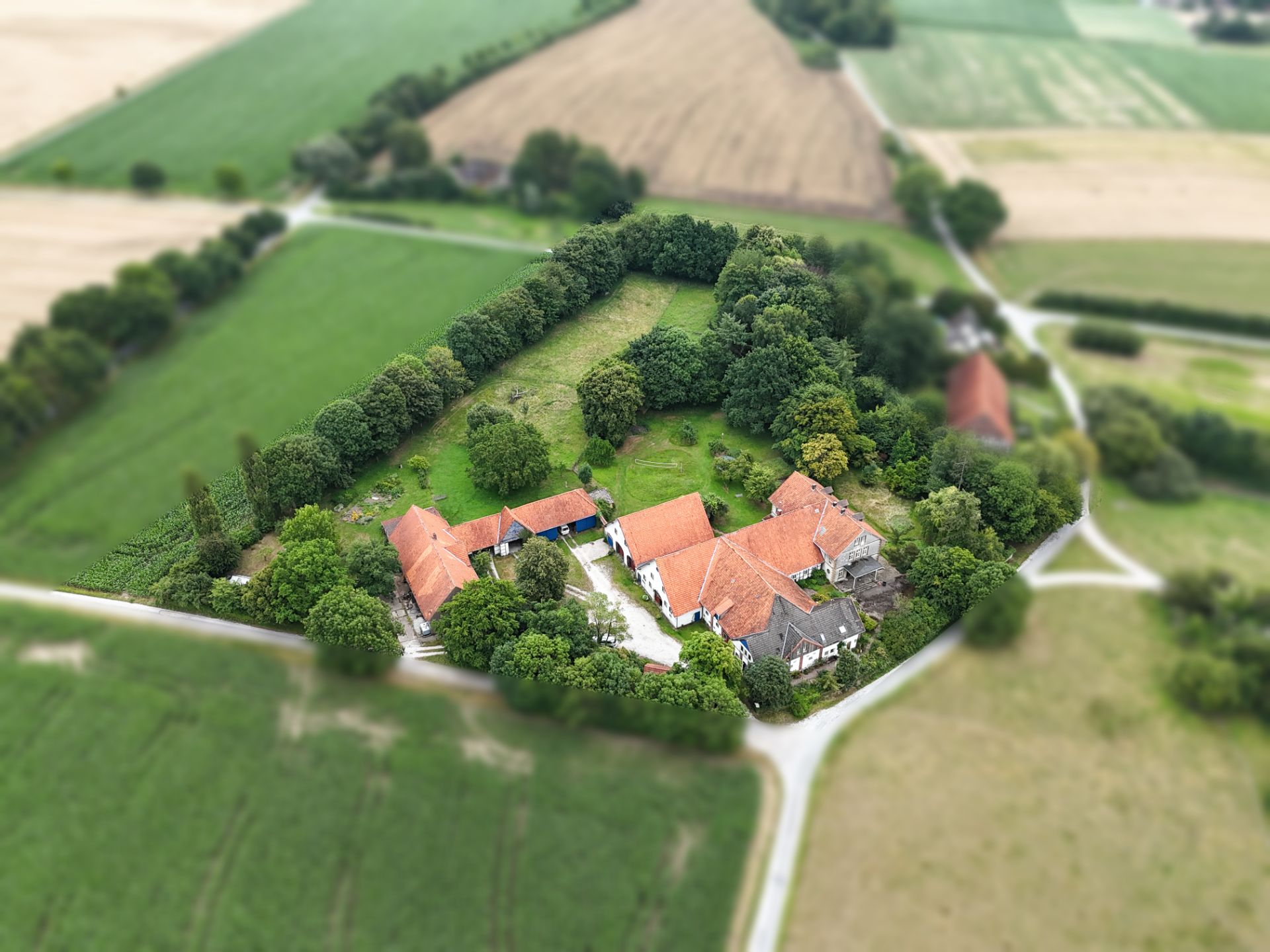 Luftaufnahme eines großen Grundstücks mit mehreren Häusern und roten Dächern in ländlicher Umgebung.