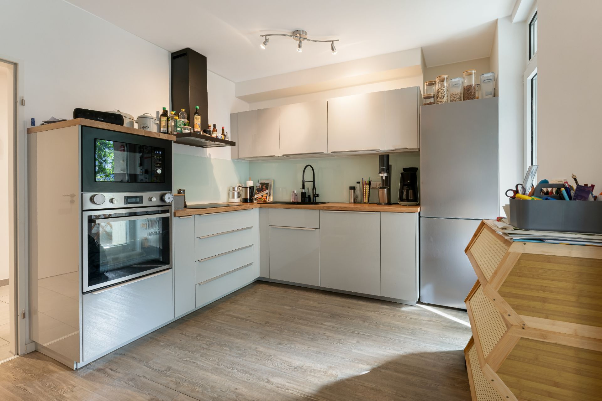 Moderne Einbauküche mit Holzarbeitsplatte, Herd, Backofen und großem Kühlschrank.