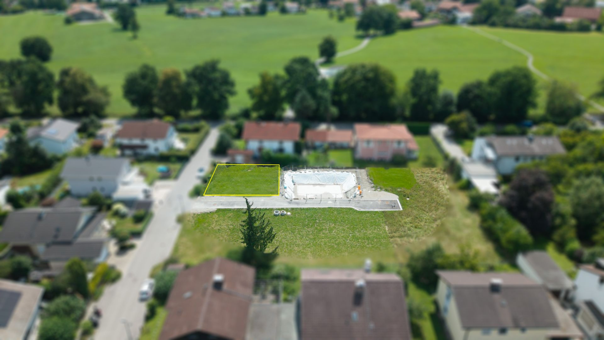 Luftaufnahme eines Wohngebiets mit Baugrundstücken und umliegenden Häusern.
