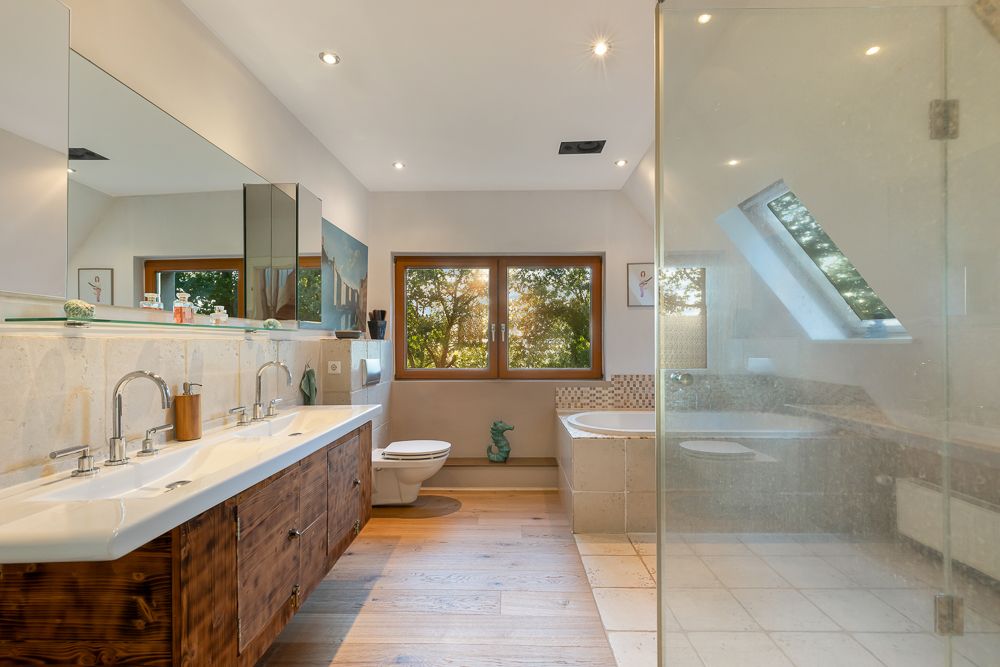 Modernes Badezimmer mit Doppelwaschbecken, Badewanne, Dusche und großem Fenster.