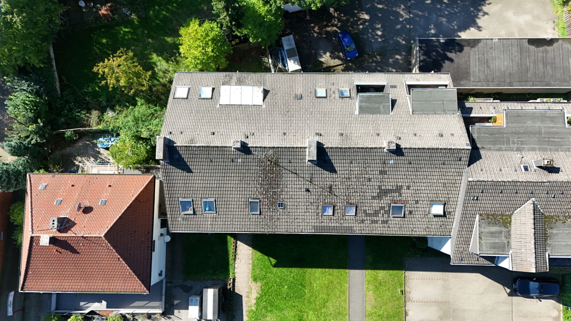 Draufsicht auf zwei Wohnhäuser mit Gärten und Wegen bei sonnigem Wetter.