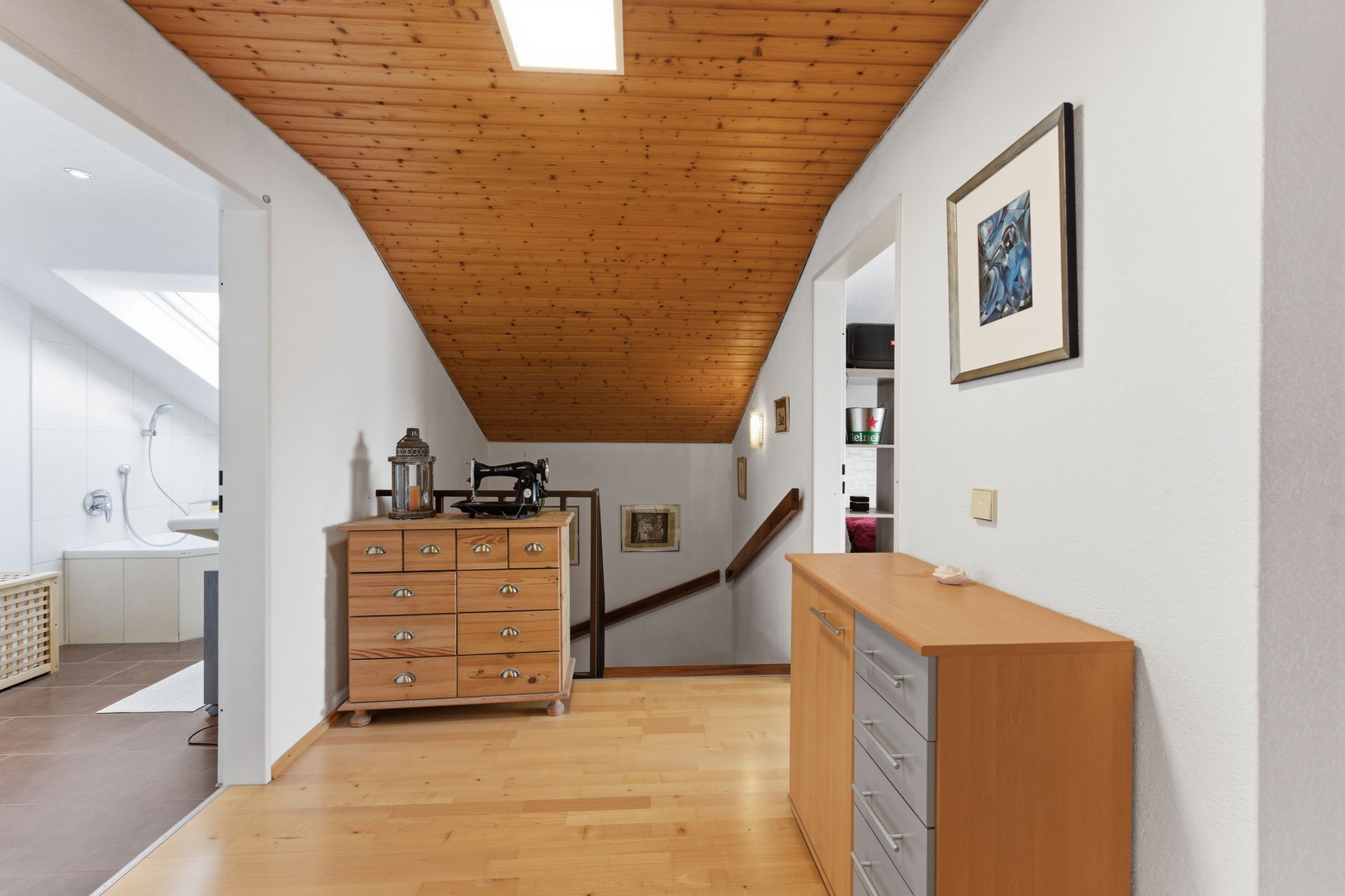 Flur mit Holzdecke, Kommoden und Zugang zu Bad und Treppe.
