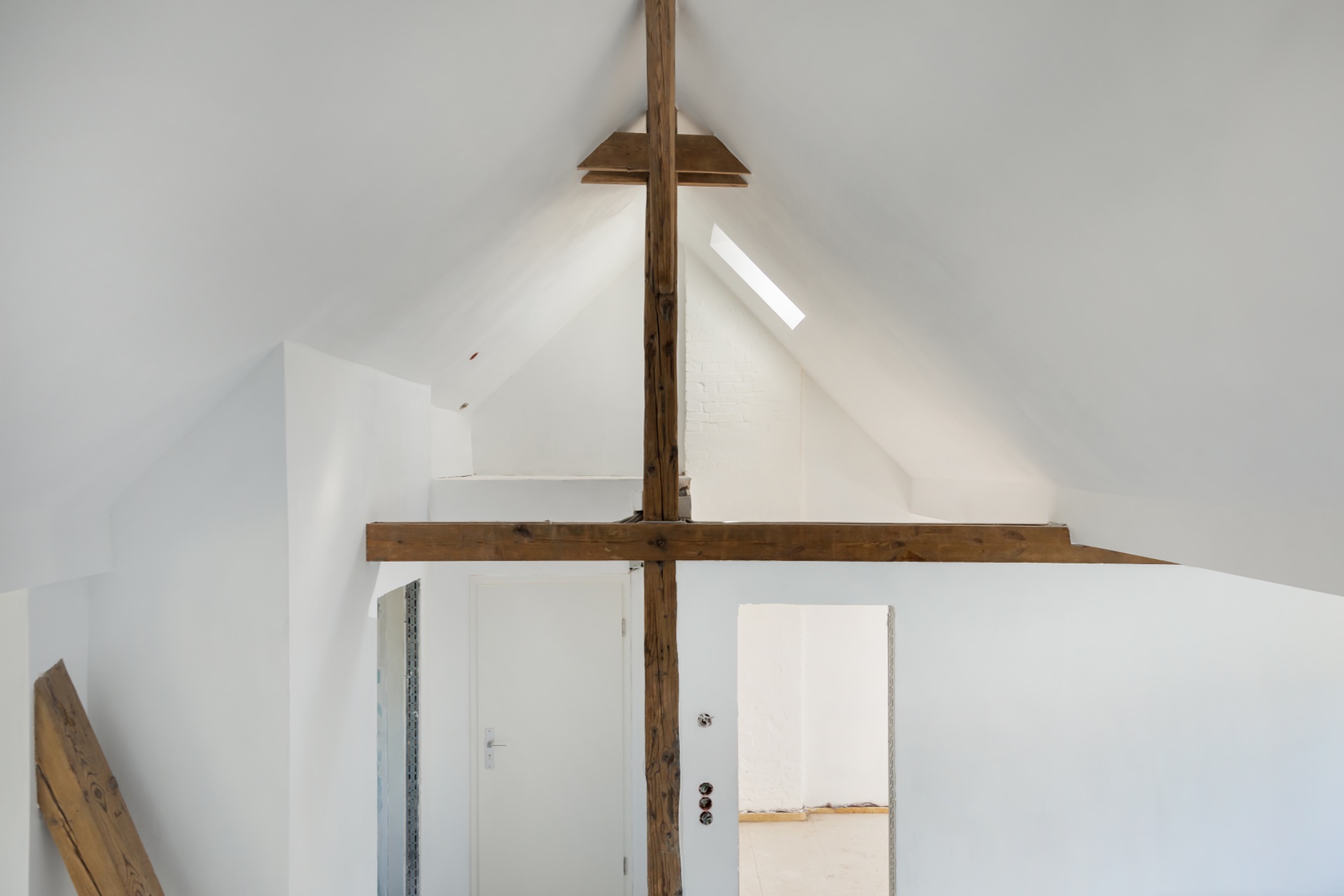 Dachgeschossraum mit weißen Wänden und sichtbaren Holzbalken.