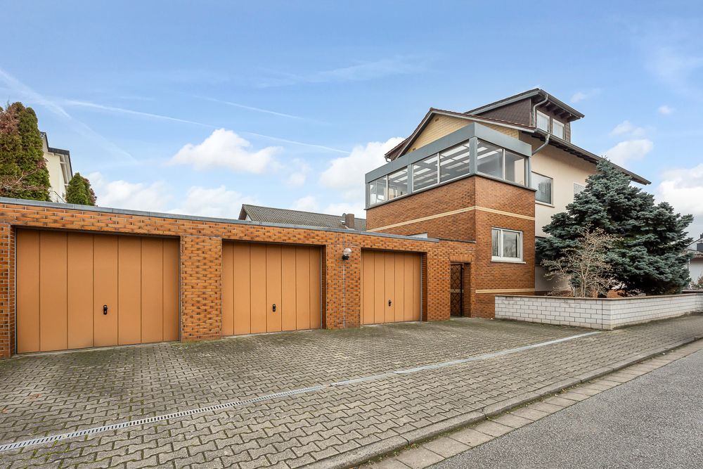 Wohnhaus mit drei Garagen aus Backstein und gepflasterter Einfahrt.