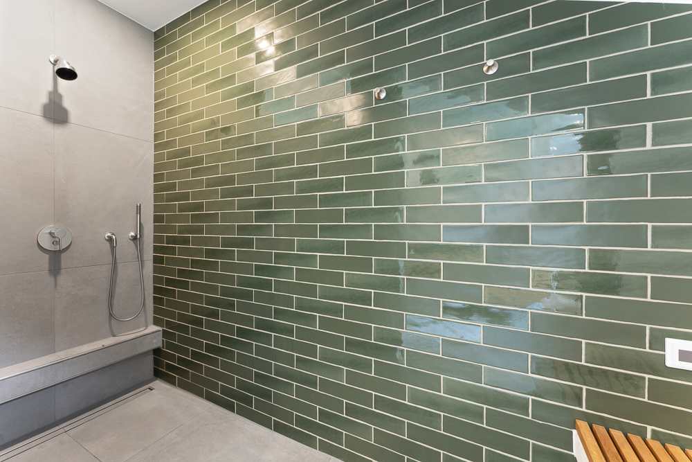 Moderne Dusche mit grüner Fliesenwand und grauen Bodenfliesen.