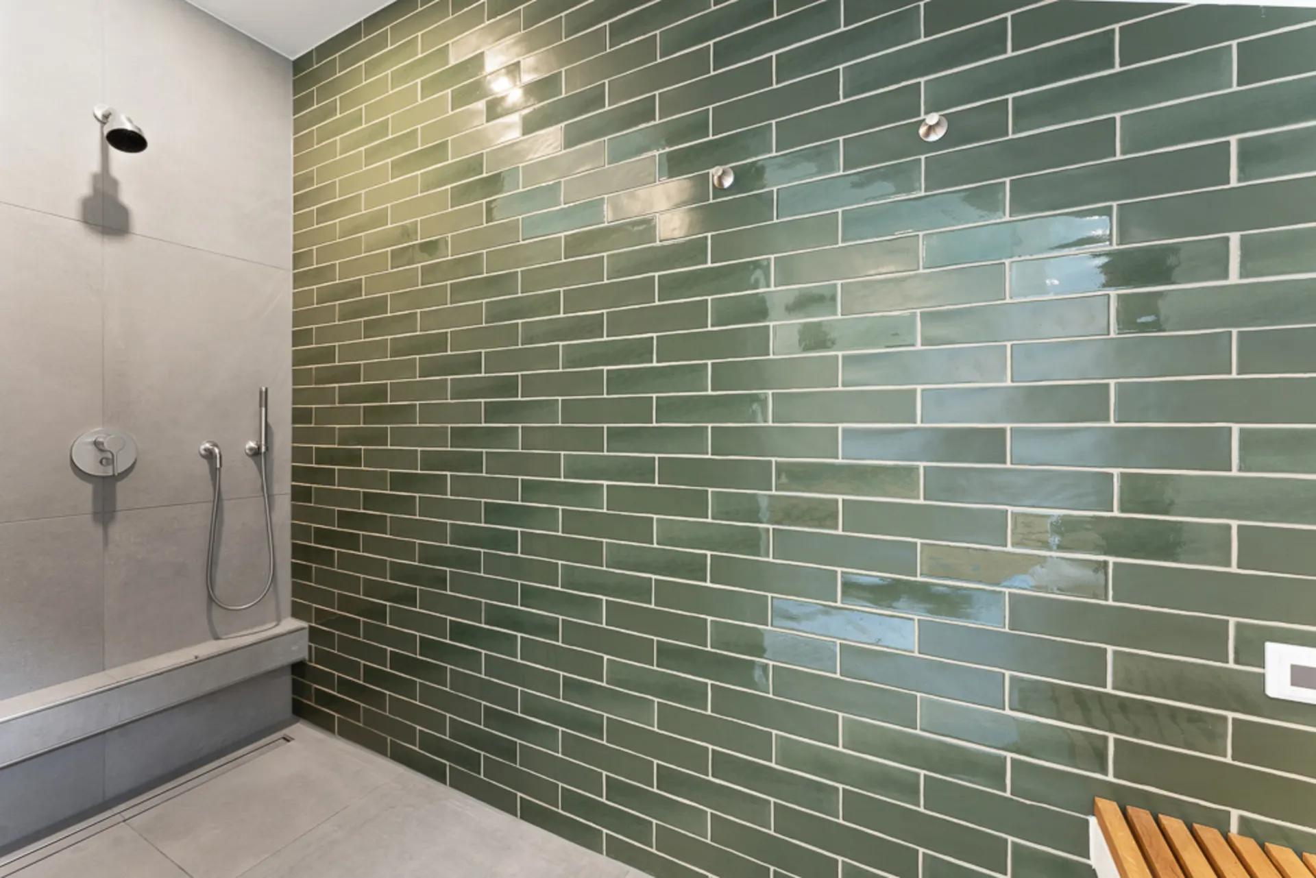 Moderne Dusche mit grüner Fliesenwand und grauen Bodenfliesen.