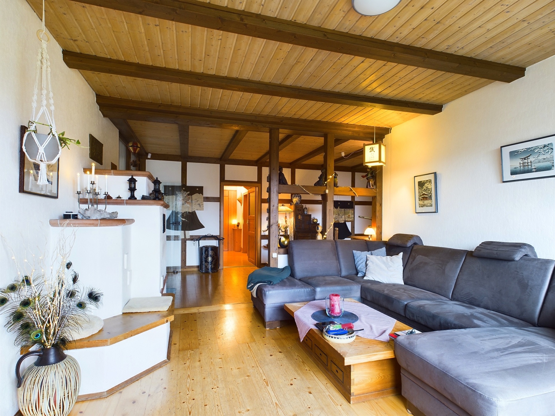 Helles Wohnzimmer mit grauem Ecksofa, Holzboden und dekorativem Tisch.