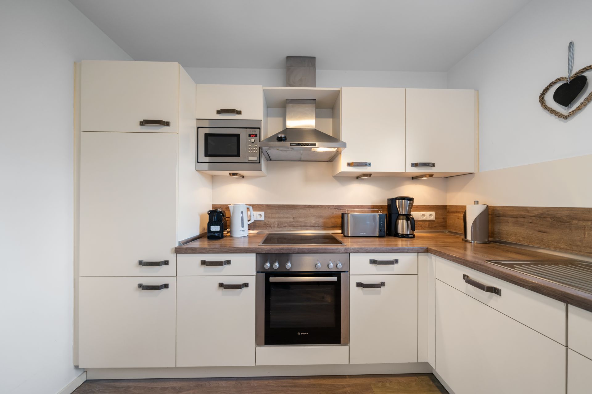 Moderne Einbauküche mit Herd, Ofen, Mikrowelle, Spüle und Kaffeemaschine.