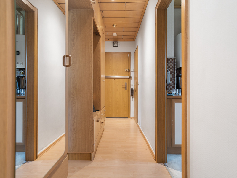 Heller Flur mit Holzboden, Holzmöbeln und Türen zu angrenzenden Räumen in einer Wohnung.