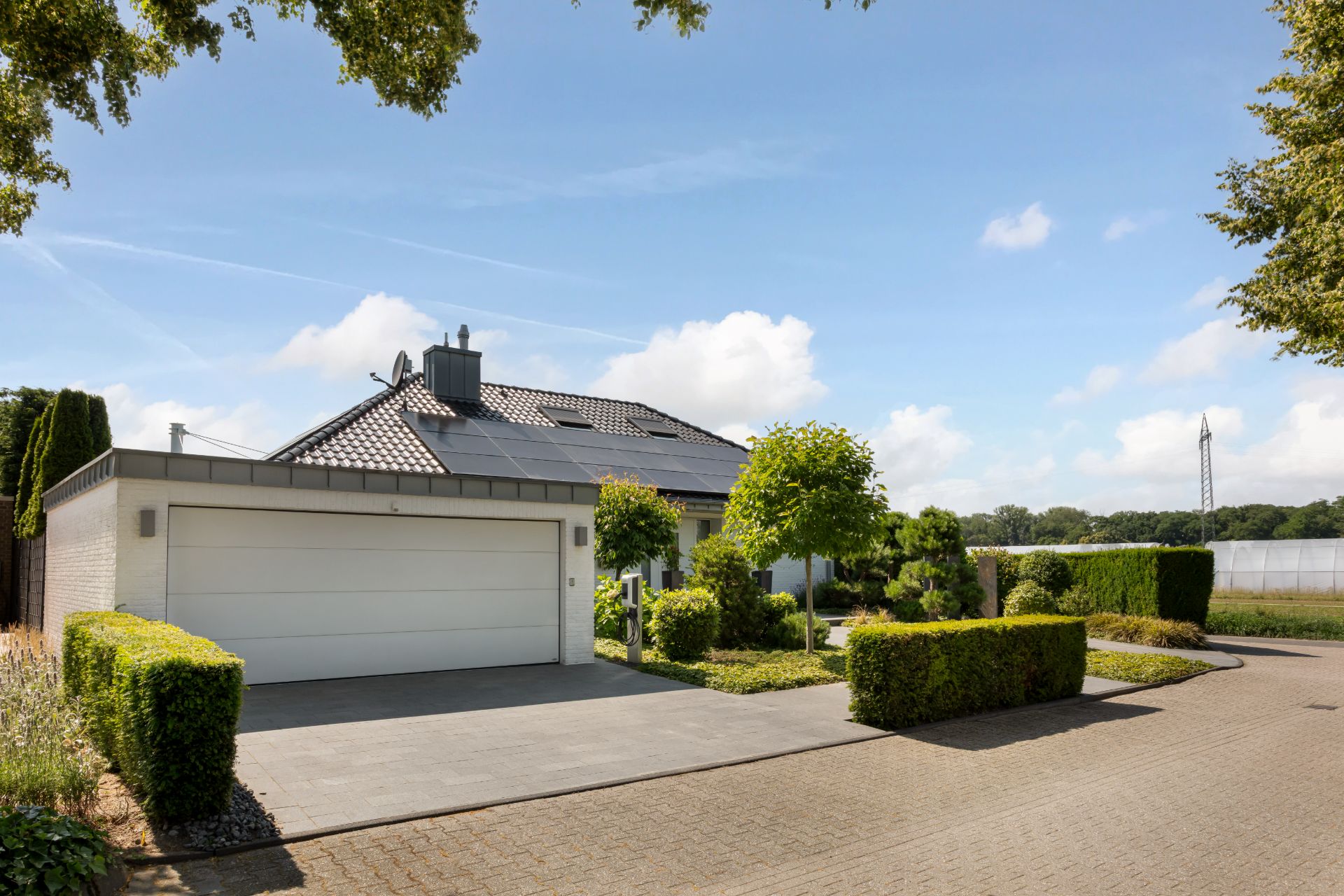 Modernes Einfamilienhaus mit großer Garage und gepflegtem Garten an einer ruhigen Straße.