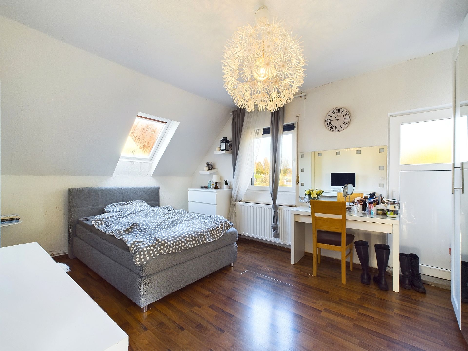 Helles Schlafzimmer mit Doppelbett, Schreibtisch, Kleiderschrank und großen Fenstern.