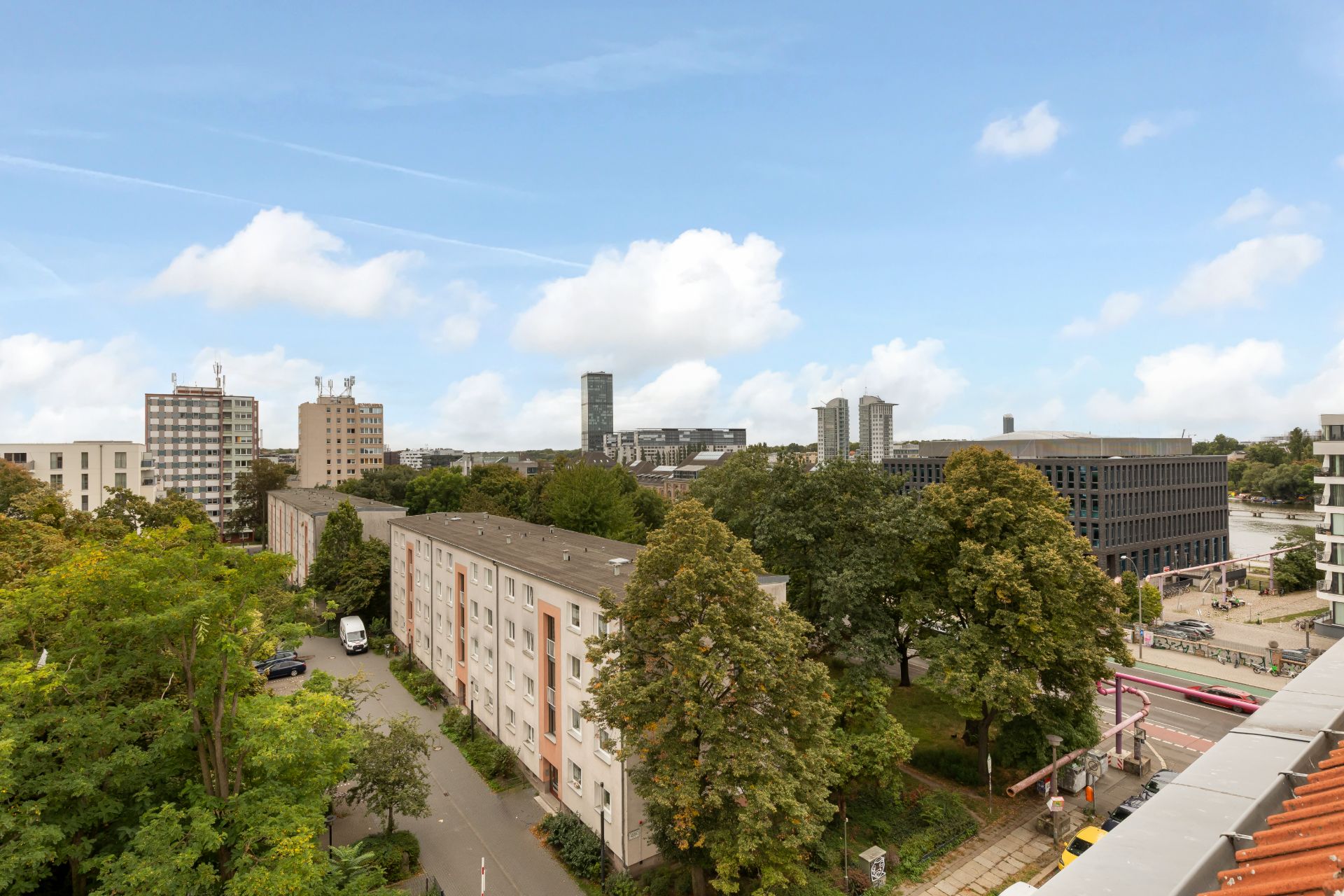 Blick auf Wohngebäude, Bäume und Straßen unter blauem Himmel mit Wolken.