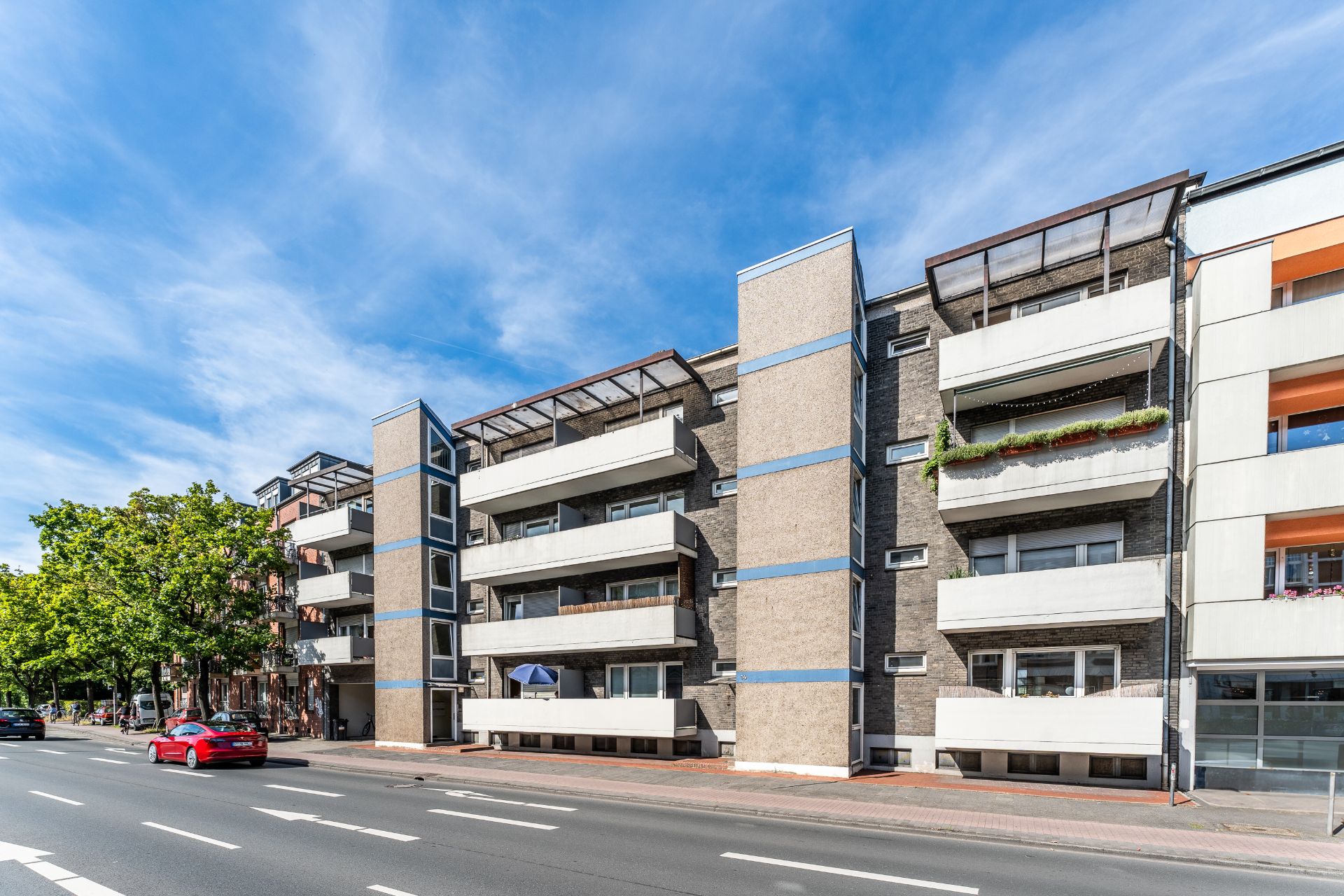 Mehrstöckiges Wohnhaus mit mehreren Balkonen an einer Straße bei Tageslicht.