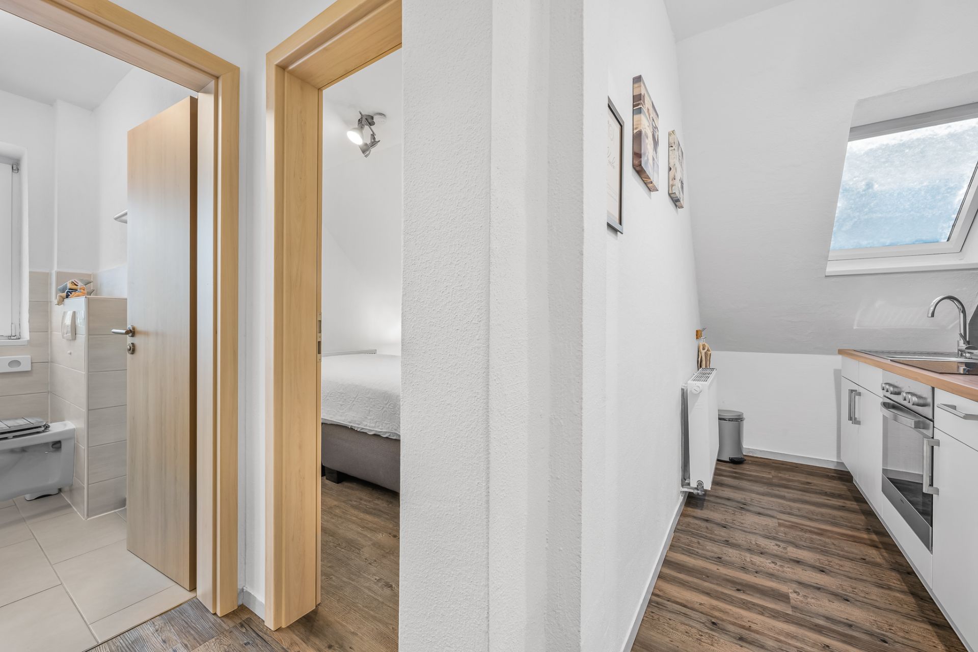 Flur mit Blick auf Bad, Schlafzimmer und Küche in einer Wohnung.