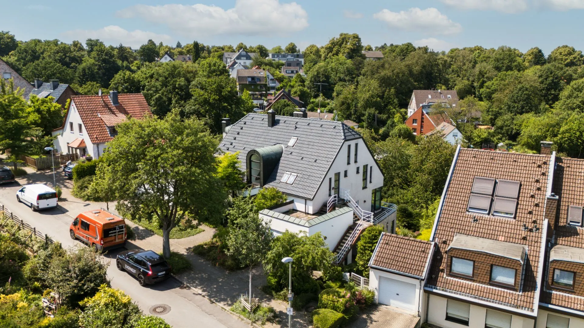 Luftaufnahme eines Wohnviertels mit mehreren Einfamilienhäusern und Bäumen.