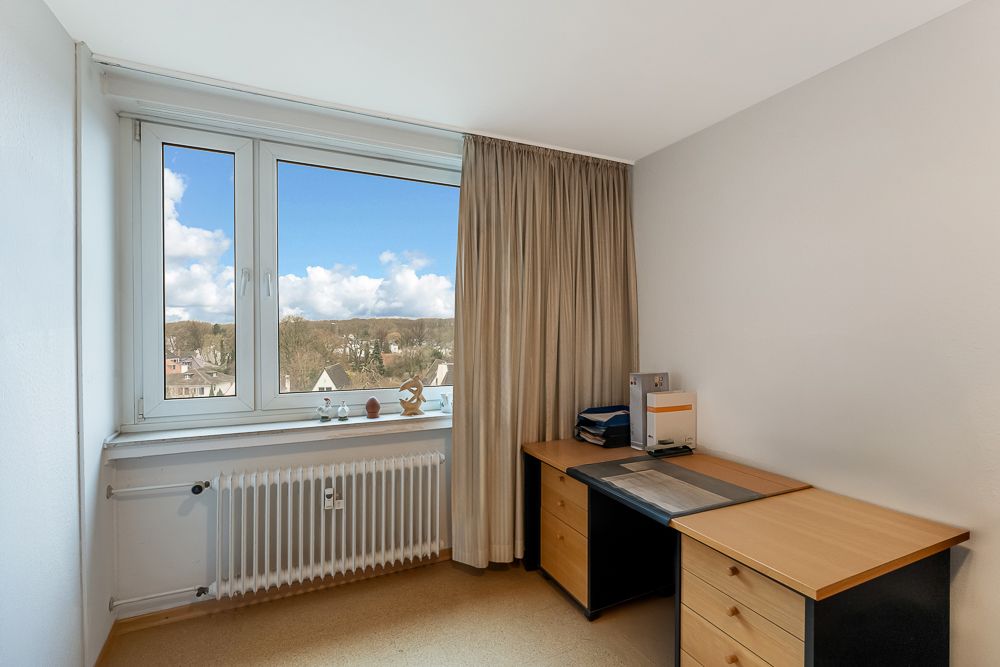 Kleines Arbeitszimmer mit Schreibtisch, Stuhl, Fenster und Blick ins Grüne.