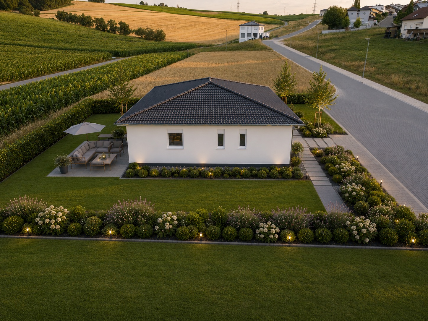 Modernes Einfamilienhaus mit Garten, Terrasse und Blumenbeeten an einer ruhigen Straße.