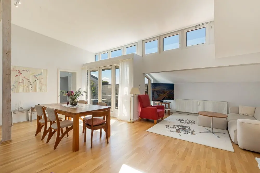 Helles Wohnzimmer mit Esstisch, Stühlen, Sofa, Sessel und großem Fenster.