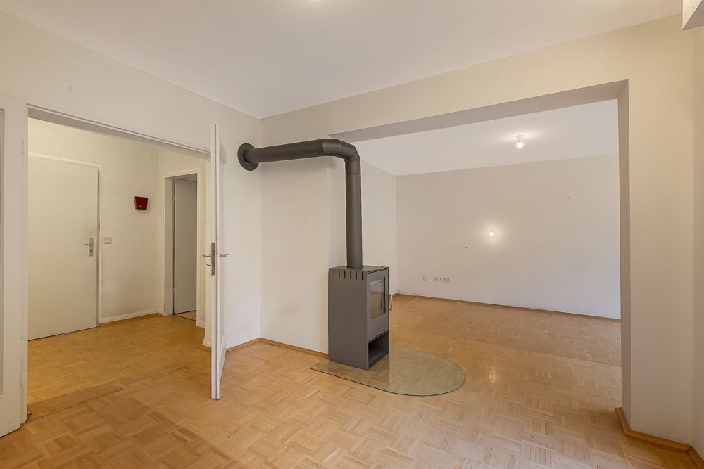 Wohnzimmer mit Holzofen, Parkettboden und offenen Türen zu benachbarten Räumen.