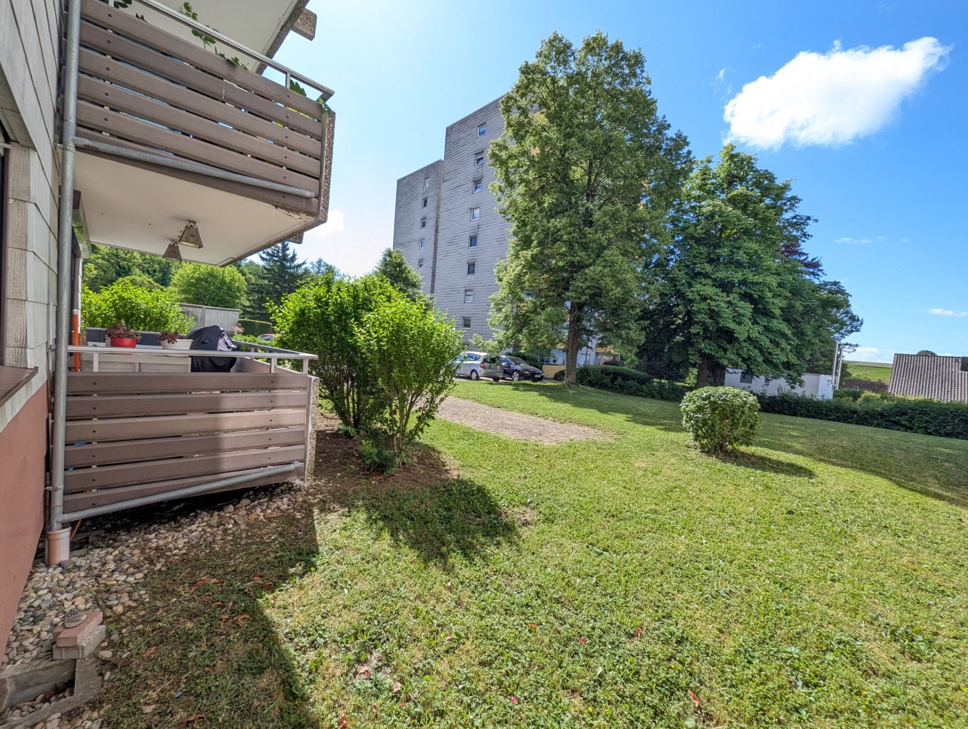 Balkon und Terrasse eines Wohnhauses mit grünem Garten und Bäumen im Freien.