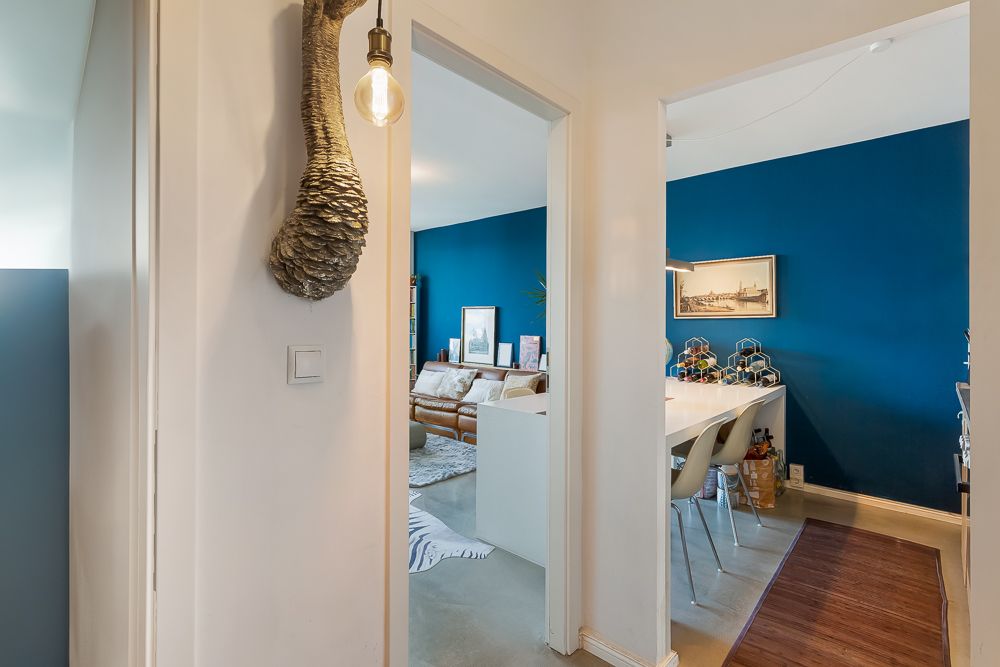 Blick vom Flur in ein Wohnzimmer und Esszimmer mit blauen Wänden und weißem Interieur.
