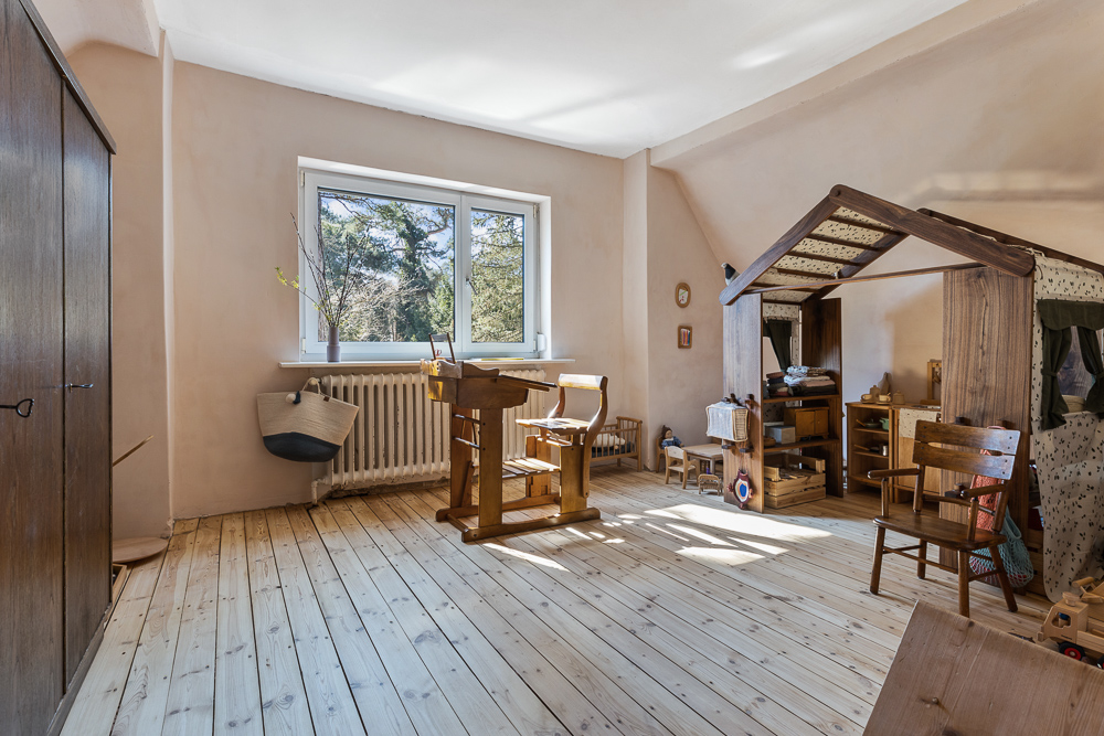 Helles Kinderzimmer mit Holzfußboden, Möbeln und Spielhaus, großes Fenster mit Ausblick.