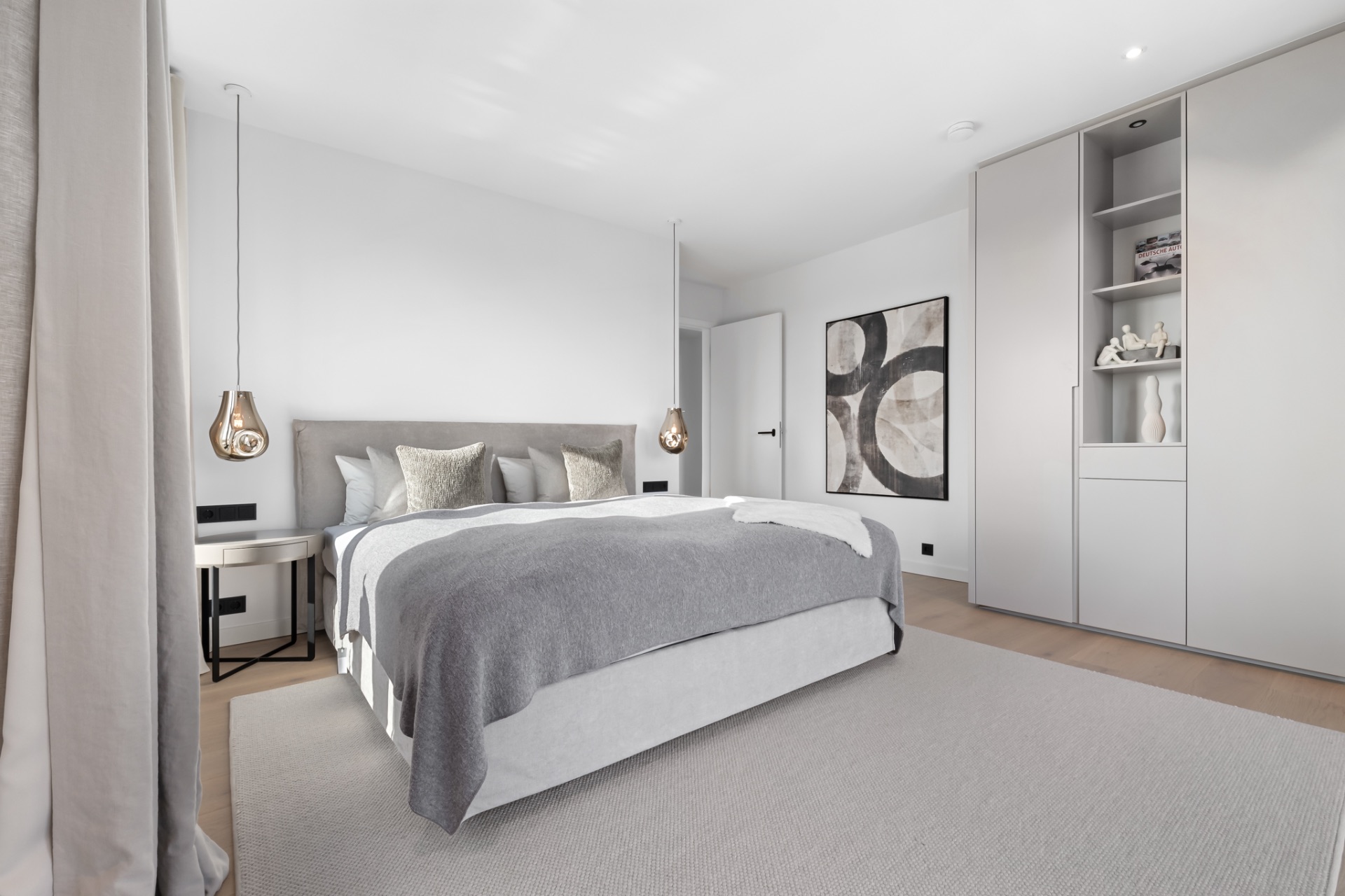 Modernes Schlafzimmer mit grauem Bett, großen Schränken und abstraktem Bild an der Wand.