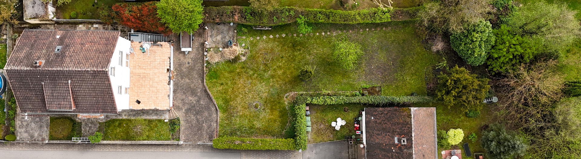 Luftaufnahme eines Wohnhauses mit Garten und benachbartem Haus mit Grünfläche dazwischen.