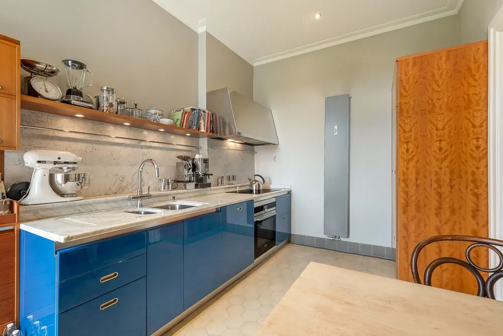 Moderne Küche mit blauen Unterschränken, doppeltem Waschbecken und Küchengeräten auf der Arbeitsplatte.