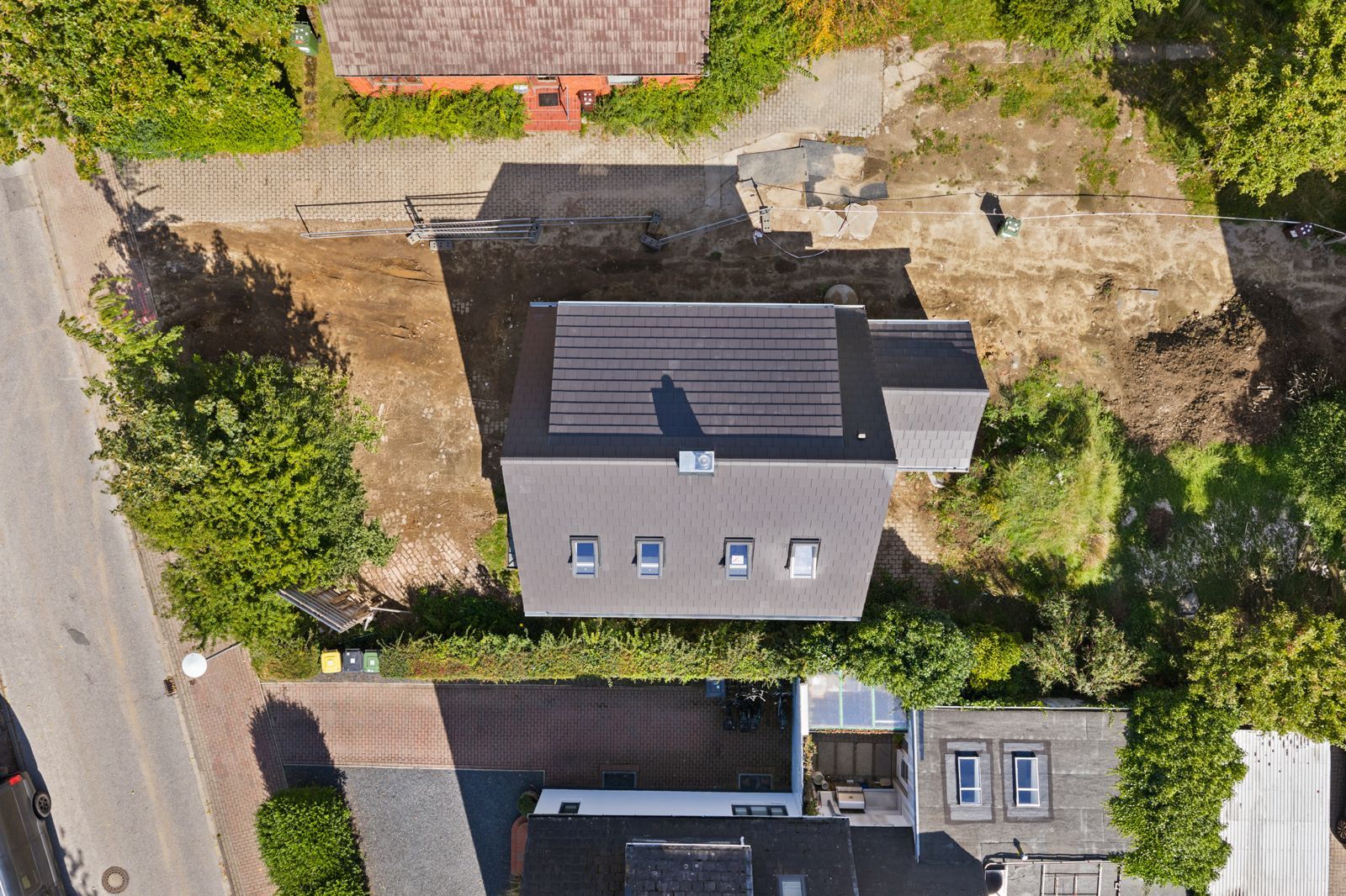 Luftaufnahme eines Einfamilienhauses mit Garten und umliegenden Straßen.