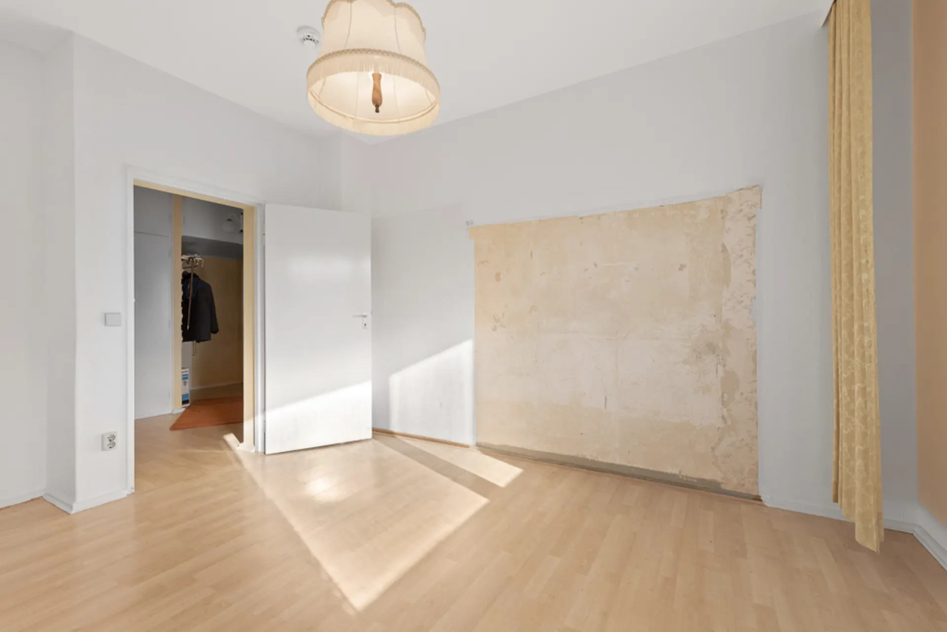 Leerer Raum mit hellem Holzfußboden und einer unvollständig gestrichenen Wand.