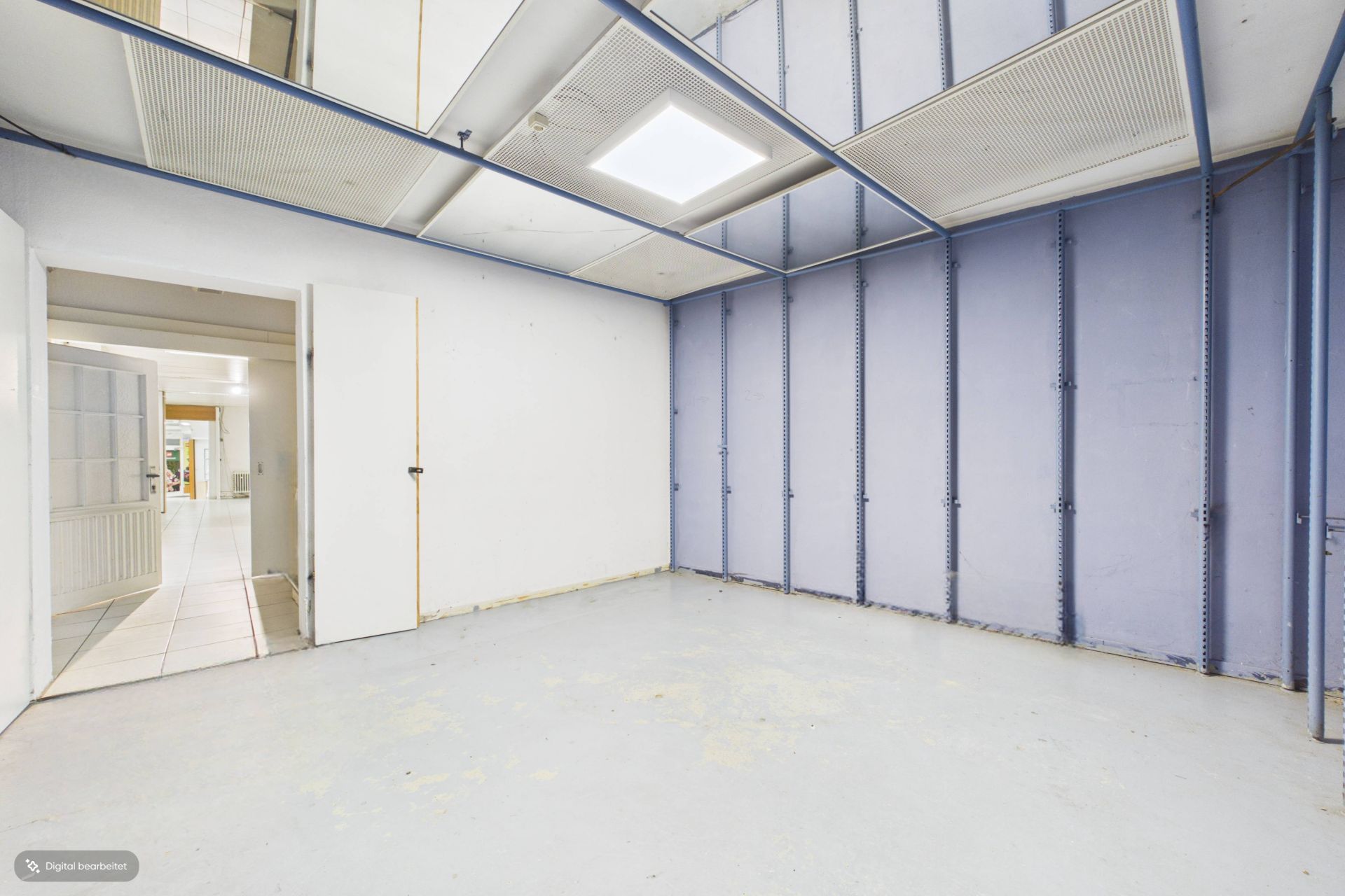 Leerer Raum mit hellblauen Wänden, abgehängter Decke und Tür zu einem Flur.