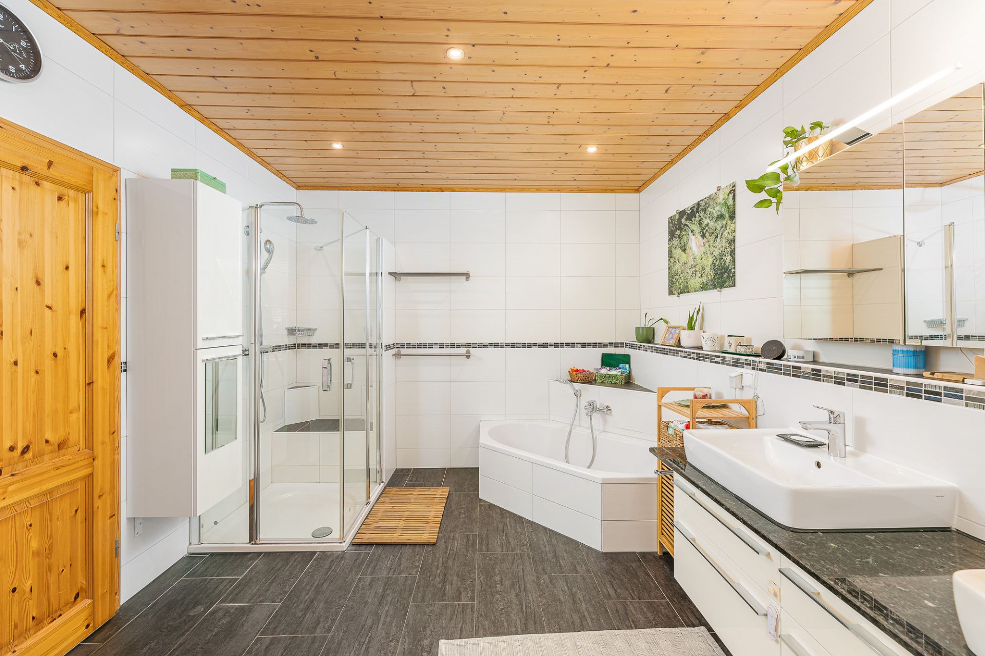 Modernes Badezimmer mit Dusche, Eckbadewanne, Waschbecken und Holzdecke.