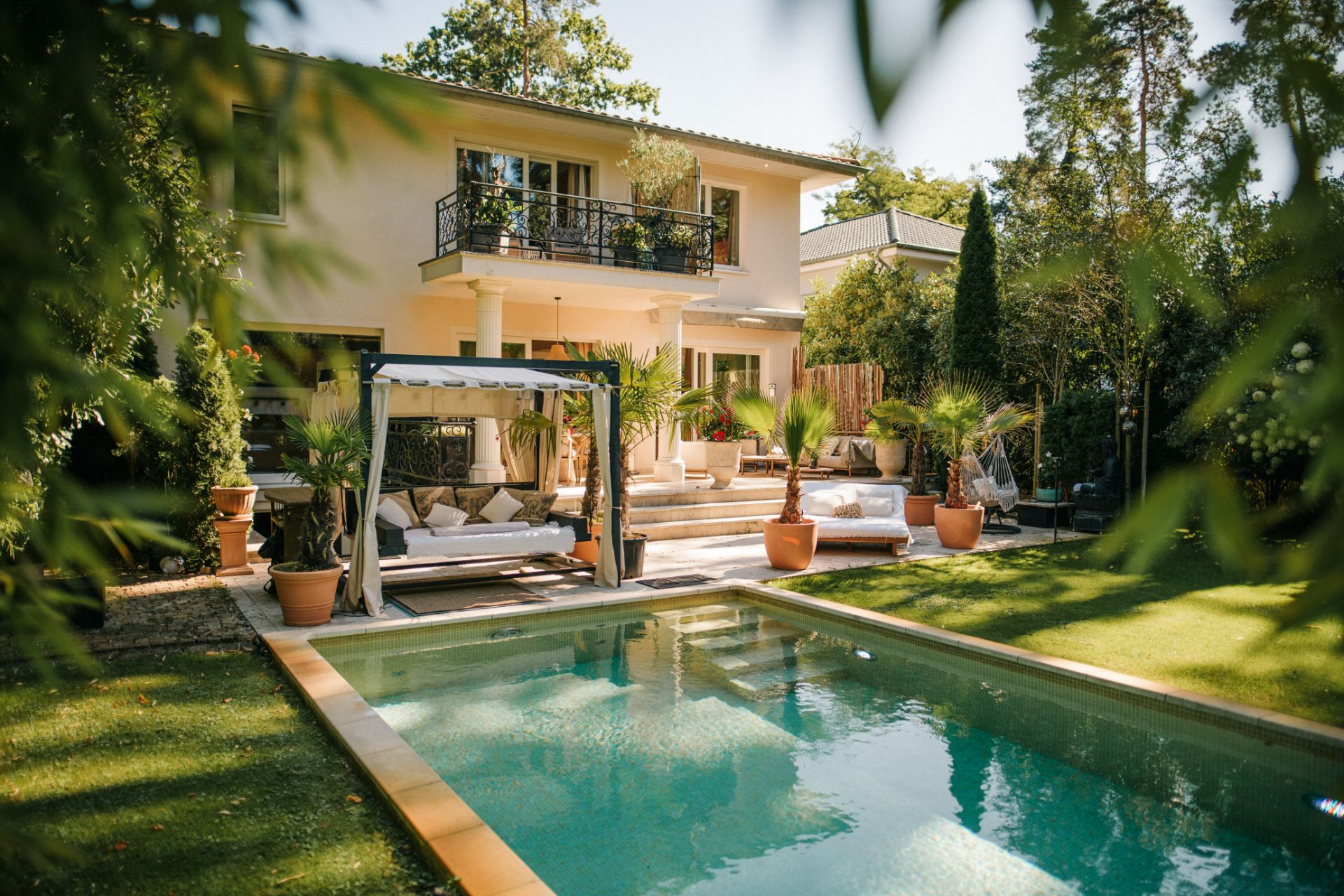 Modernes Wohnhaus mit Terrasse, Pool, Liegen und Pflanzen im Garten.